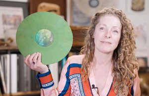 Anouk Rijnders von Record Industry hält eine recycelte grüne Schallplatte in den Händen und lächelt