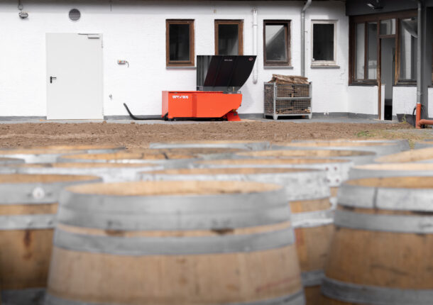 In the background, an orange shredder from WEIMA; in the foreground, barrique barrels.