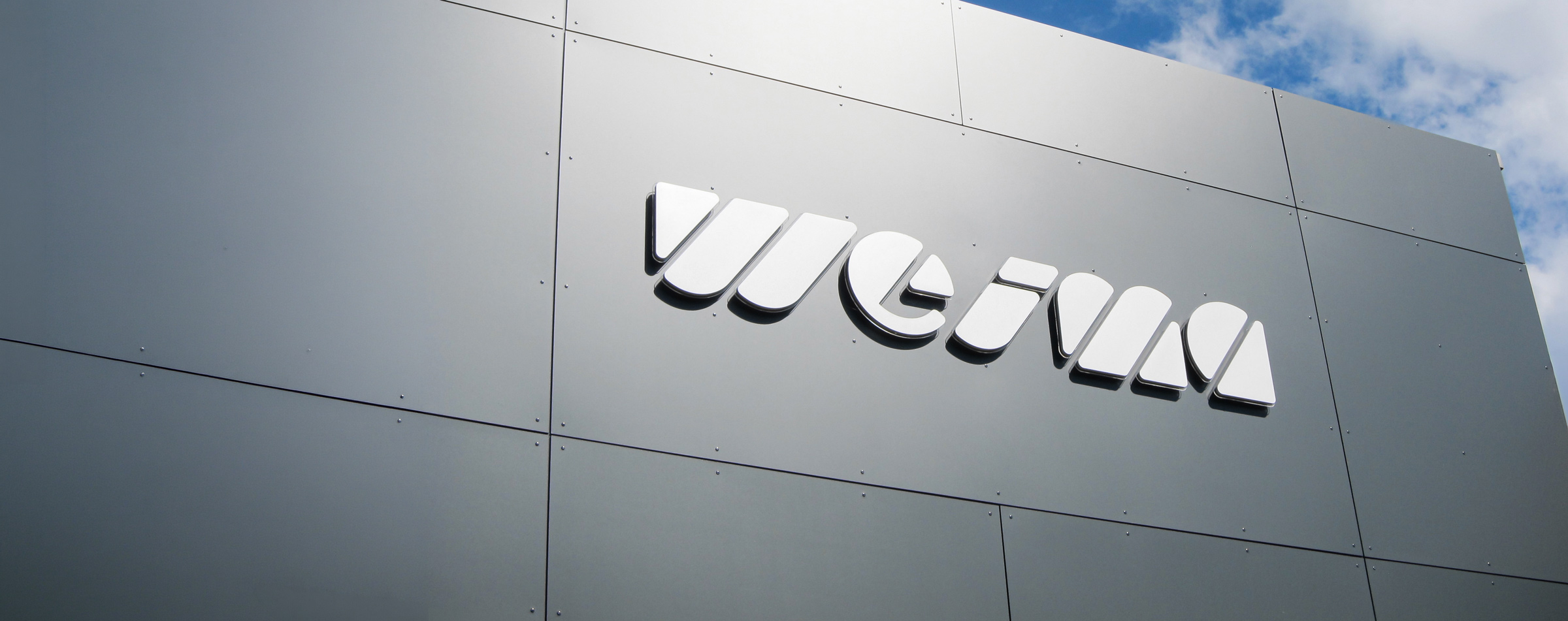 WEIMA Logo auf grauer Fassade mit blauen Himmel im Hintergund