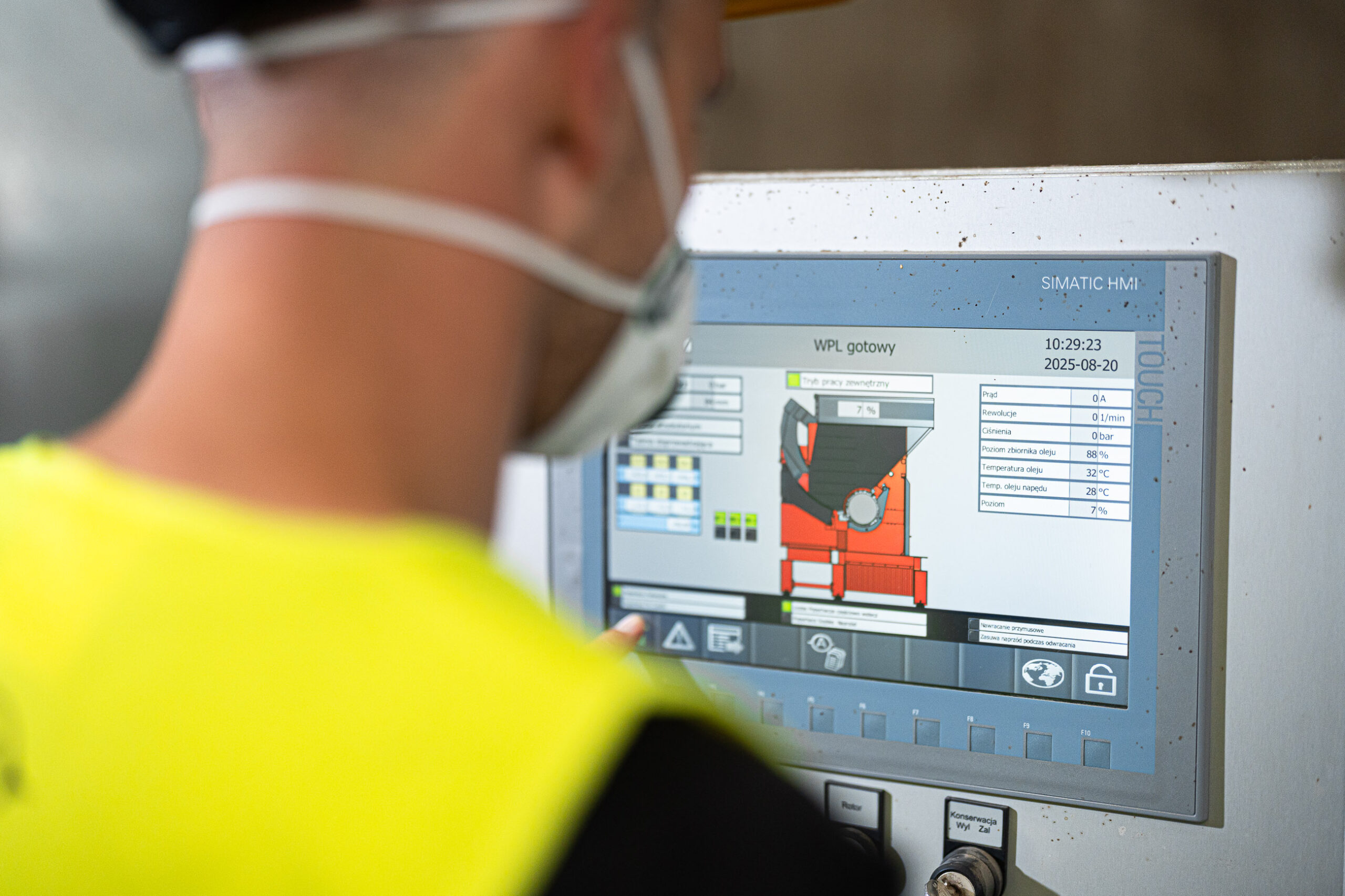 Mitarbeiter von Euro Eko mit gelber Warnweste steht von Siemens HMI, die einen weima shredder zeigt