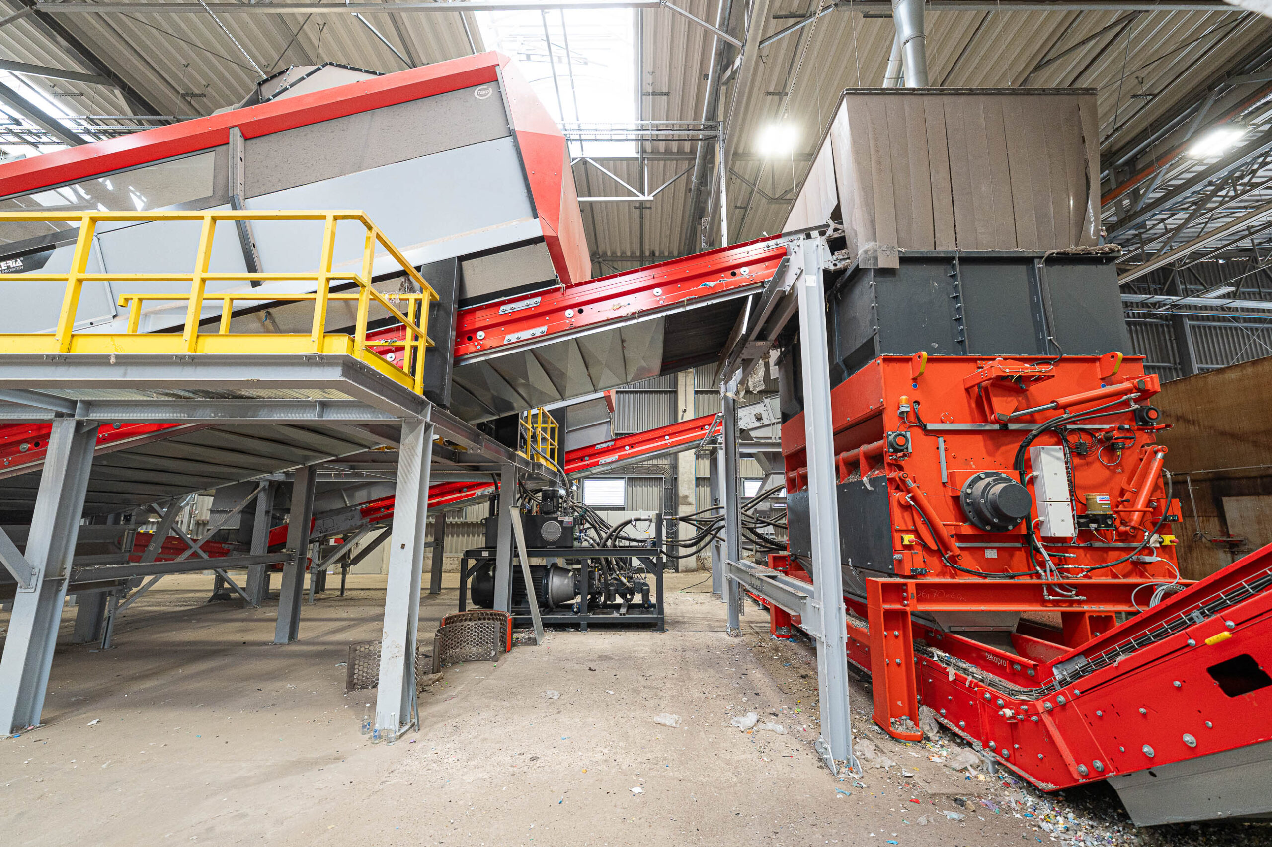 Ein orangener WEIMA PowerLine shredder, verbunden mit einem großen Förderband