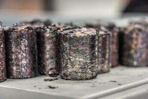 Nahaufnahme mehrerer dunklen Briketts aus Kunststoff und Kupfer