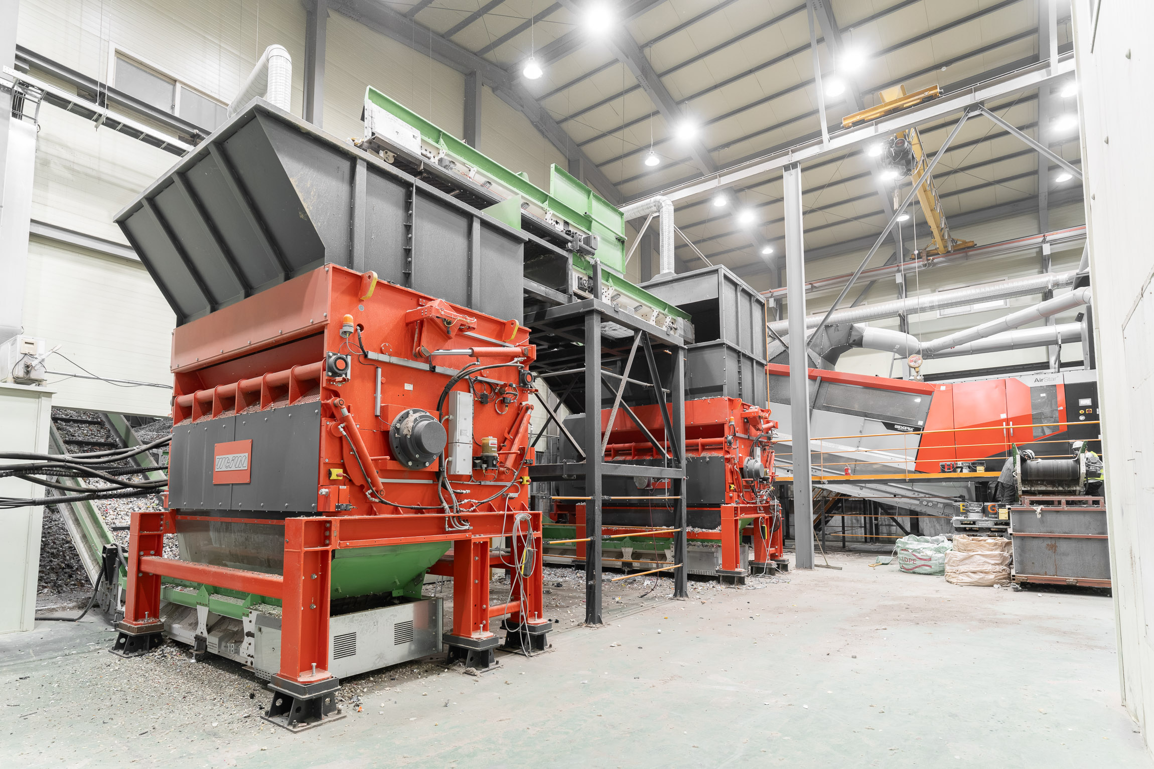 Two large orange shredders connected by conveyor belts in a warehouse