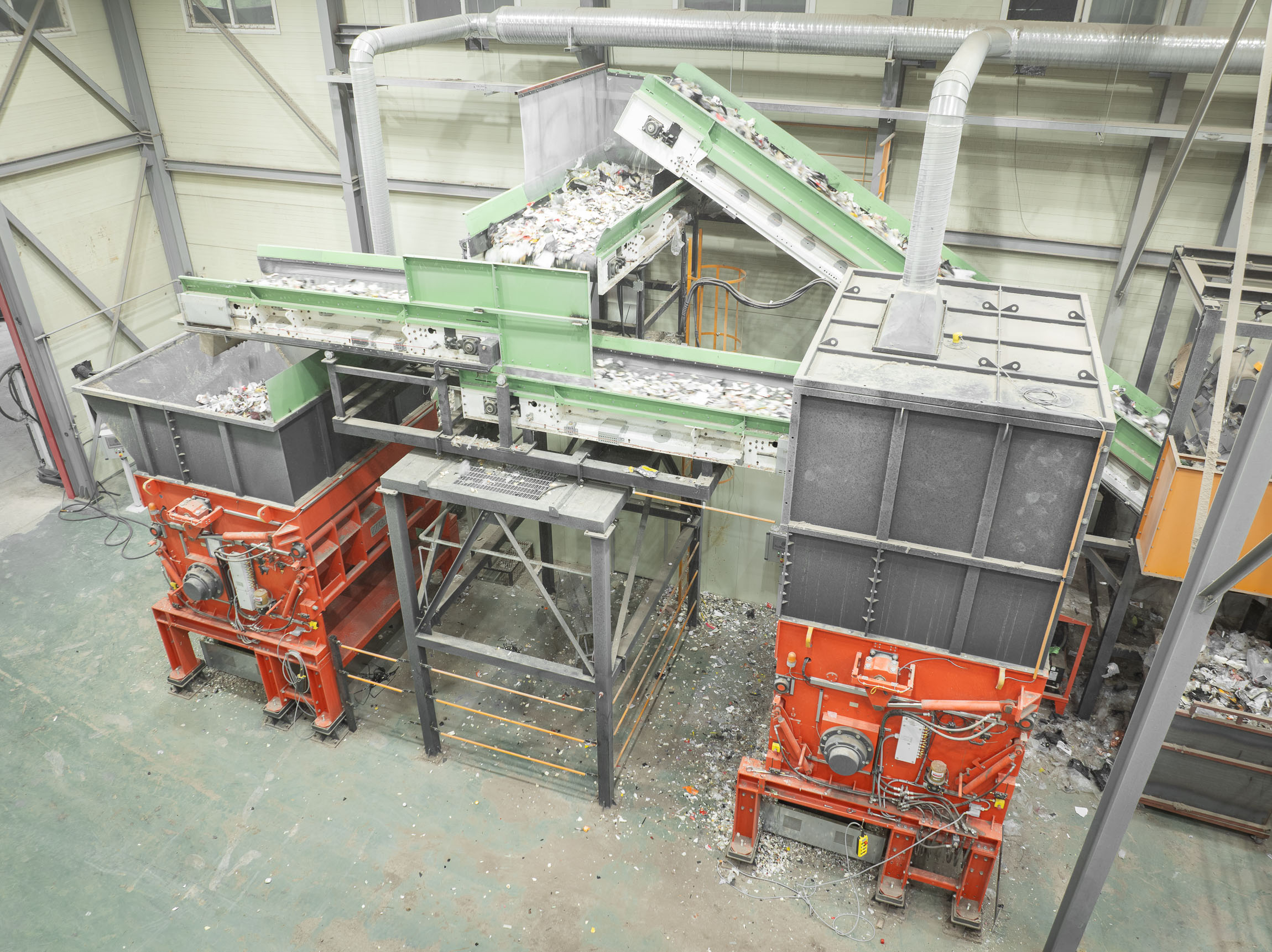 Aerial view of two large orange shredders in a warehouse, connected by conveyor belts