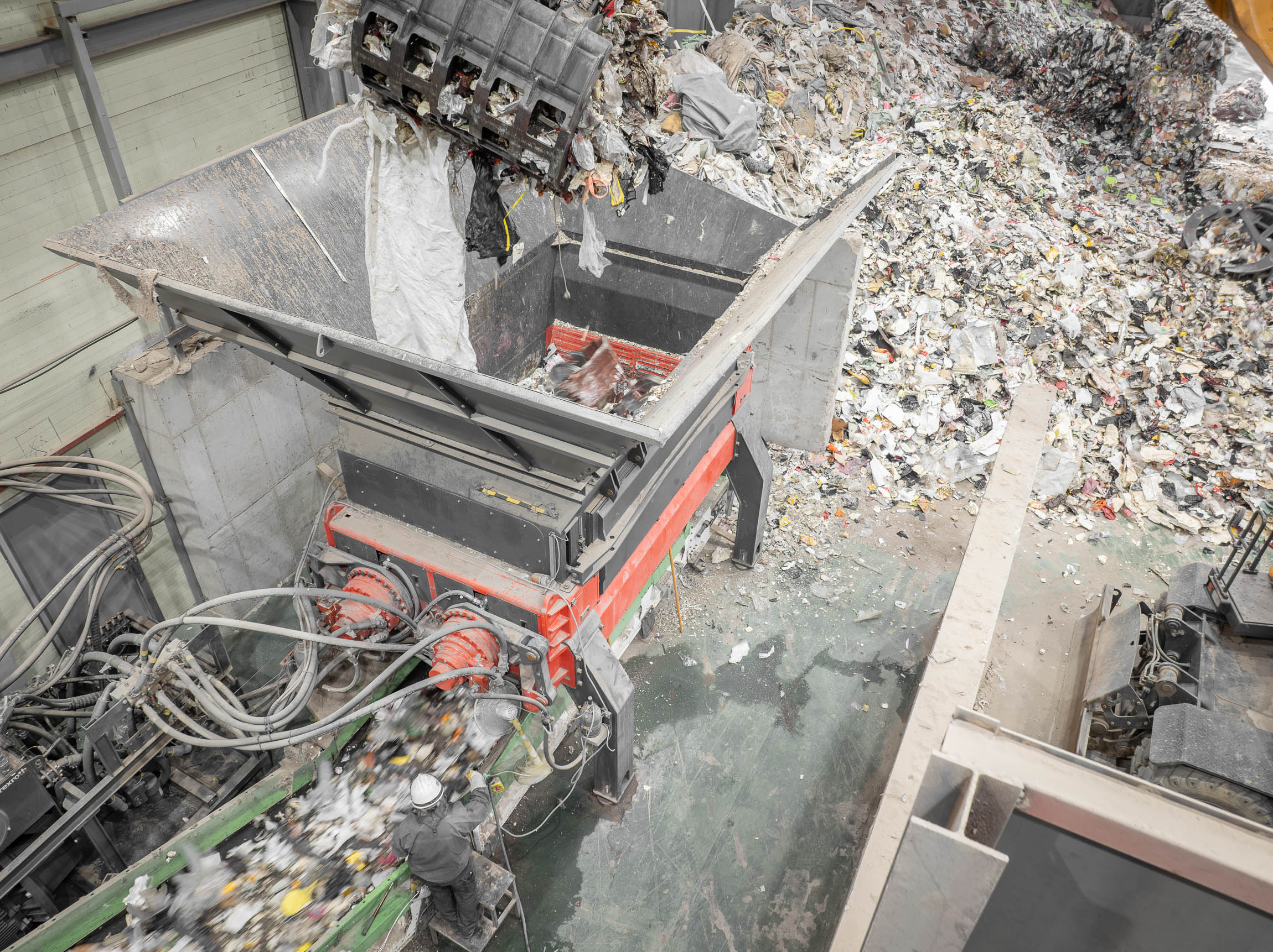Aerial view of a twin-shaft shredder being loaded with waste by an excavator