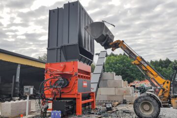Radlader befüllt WEIMA PowerLine Shredder mit Müllcontainern und Plastikrohren