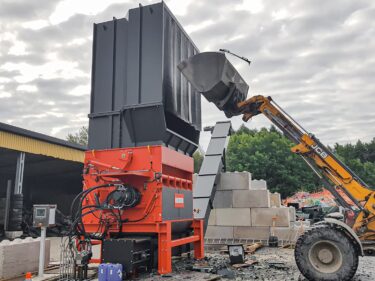 Radlader befüllt WEIMA PowerLine Shredder mit Müllcontainern und Plastikrohren
