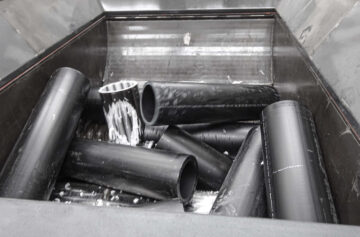 HDPE Altrohrabschnitte befinden sich im Trichter der Maschine am Rotor und werden geshreddert