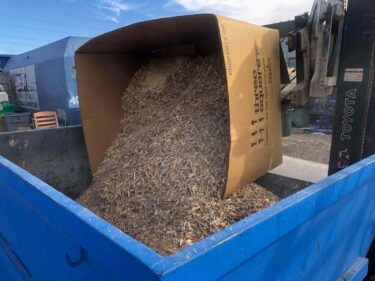 shredded wood is placed in a dumpster for recycling