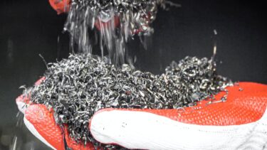 Geshredderte Aluspäne in einer Hand mit rotem Handschuh