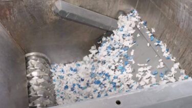 Ein WEIMA Schredder verarbeitet einen IBC Container zu kleinen Stücken. Die Schwinge presst den Container zum Schreddern gegen den Rotor