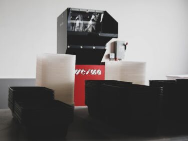 a WEIMA granulator sits behind a stack of clear and black take-away containers