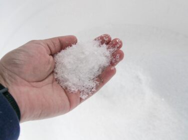 A hand holds clear plastic flakes.