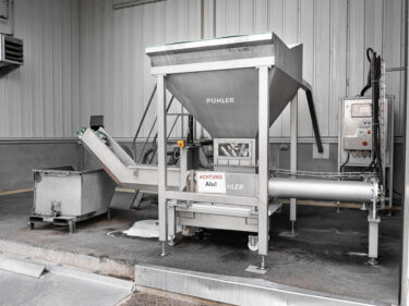 dosen pressmaschine von weima aus edelstahl in einer halle mit kippcontainer