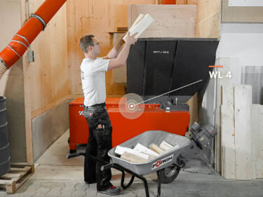 employee fedding the weima wood chipper manually with wood waste
