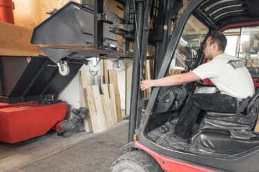 gabelstapler schüttet holzabfälle in einen orangenem weima shredder