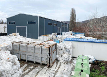 Grau produktionshalle mit kunststoffmüll in ballen im vordergrund