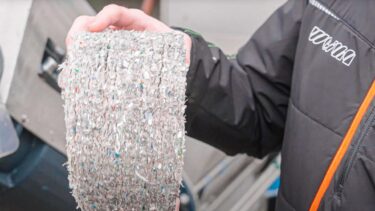 man holds pressed disc made of plastic fine parts in his hands