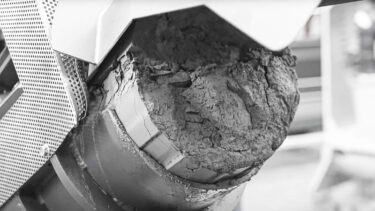 dried and compressed grinding sludge on discharge pipe of a puehler press