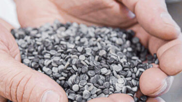 Secondary plastic raw material granulates inside a palm of a hand
