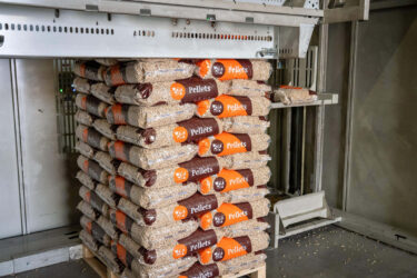 ein Stapel mit Holzpellets Säcken der gerade gefüllt wird