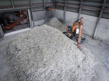Ein Berg von zerkleienerten Siedlungsabfällen und ein Bagger