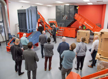 WEIMA CEO points at a conveyor between two WEIMA shredders.