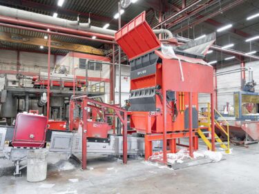 Plastic film shredder with conveyor belt inside a production halle