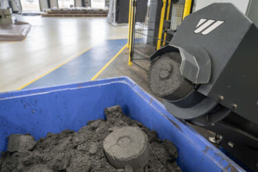 Der nahezu trockene Schleifschlamm wird aus dem Austragsrohr der WEIMA C.200 Presse gepresst