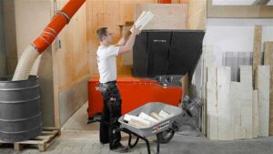 Mann befüllt einen orangenen WEIMA Holzschredder mit Restholzabschnitten