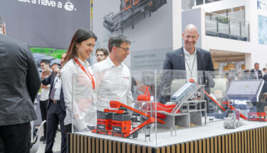 Kay Schulte, WEIMA CSO, auf der IFAT 2024 in München mit zwei Besuchern in weißen Hemden vor einem 3D-Druck Modell