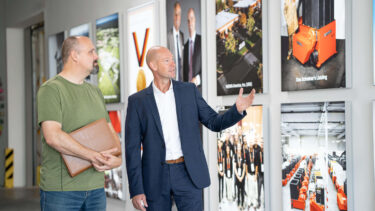 Kay Schulte in der WEIMA Unternehmenszentrale vor Fotos and einer weißen Wand