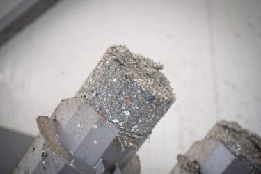 Dewatered and compressed gray lumps of plastic fine parts on the discharge pipes of a WEIMA C.200 Duo