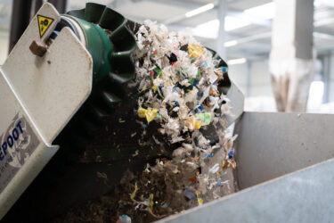 A lot of shredded colorful plastic trash falling from a conveyor belt.
