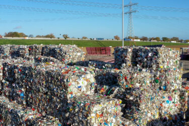 Ein Menge gestapelter Ballen mit bunten Post-Consumer Kunststoff auf einer Recyclinganlage