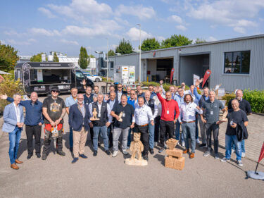 Eine Gruppe an lachenden Männern vor einem Firmengebäude.