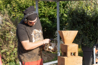 Ein Mann schnitzt mit einer Kettensäge aus einem Holzblock einen WEIMA Shredder