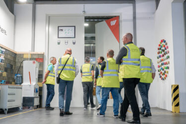 Männer in Warnwesten laufen durch eine Industriehalle