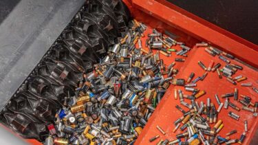 A large number of used batteries in an orange shredder during shredding