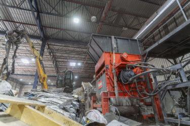 Ansicht von der Seite auf einen WEIMA Shredder. Material zur Zerkleinerung liegt im Bereich vor dem Shredder, ein Bagger befördert es in den Shredder
