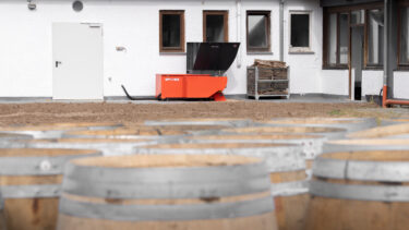 In the background, an orange shredder from WEIMA; in the foreground, barrique barrels.