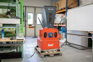Ein kleiner oranger Shredder in einer kleinen Lagerhalle