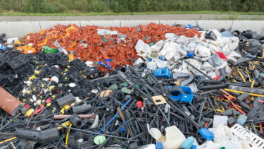 Luftaufnahme von einem Berg an Harkunststoff Abfällen auf einer Recycling Anlage