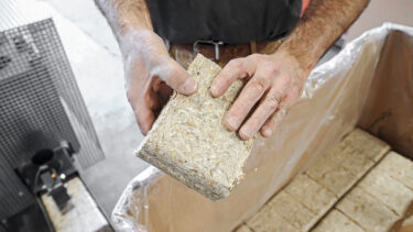 Wood dust and wood chip briquette from a TH 1200 held in hands