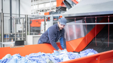 An employee places textiles on a conveyor belt