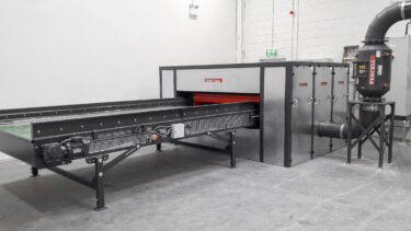 A WEIMA horizontal shredder with a conveyor belt housed in a custom-built soundproof enclosure.