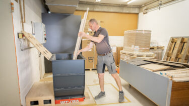 A worker in a workshop feeding long wooden strips into a WL 4 shredder