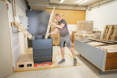 Mitarbeiter in einer Werkstatt, der lange Holzleisten in einen WL 4 Shredder einsetzt