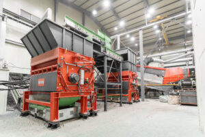 Two large orange shredders connected by conveyor belts in a warehouse