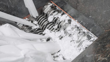 A view into the hopper of the WEIMA ZM 50 four-shaft shredder, which is currently shredding white nonwoven fabric